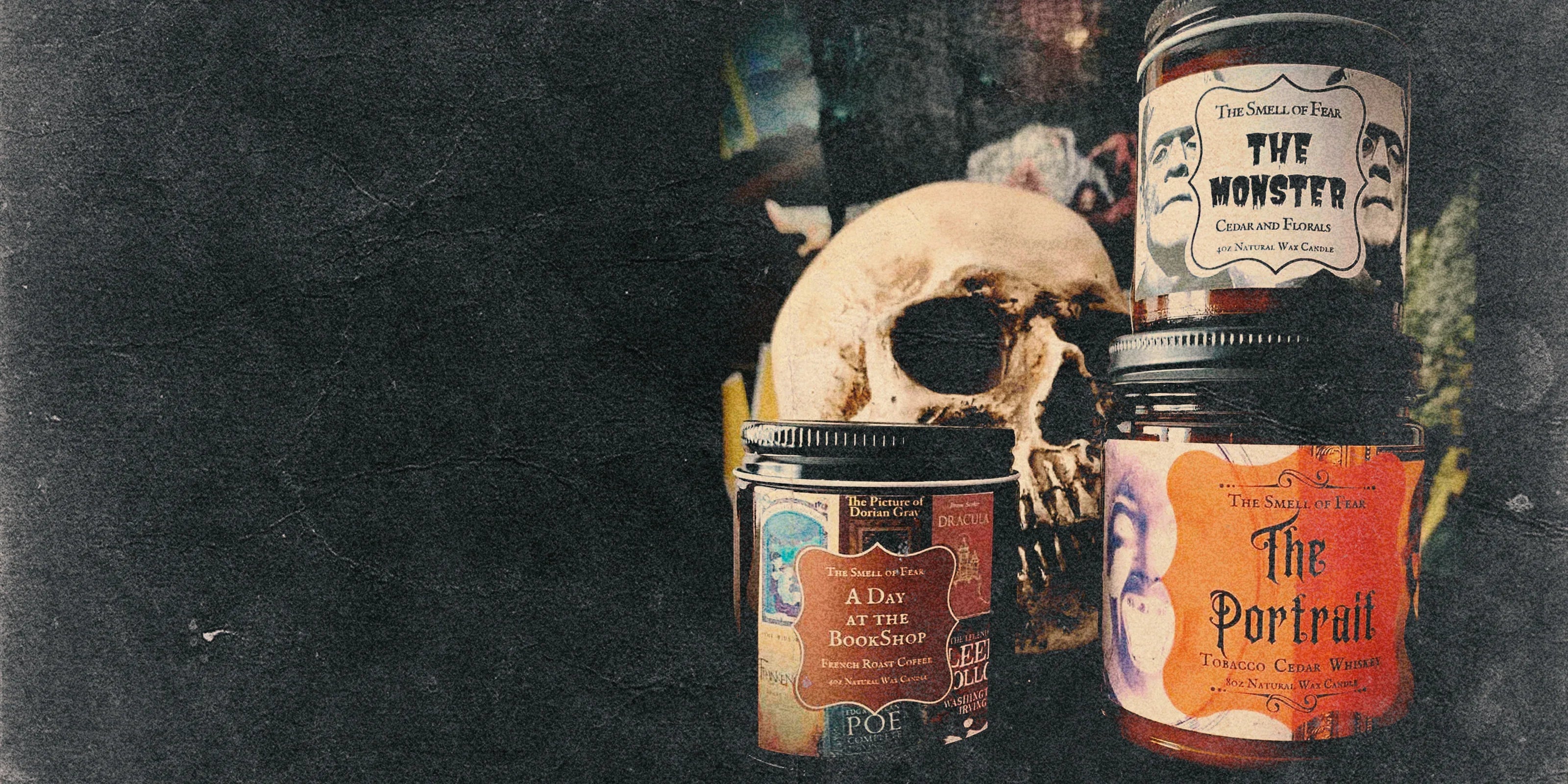 Three horror-themed candles with vintage labels beside a skull, creating a spooky gothic scene.