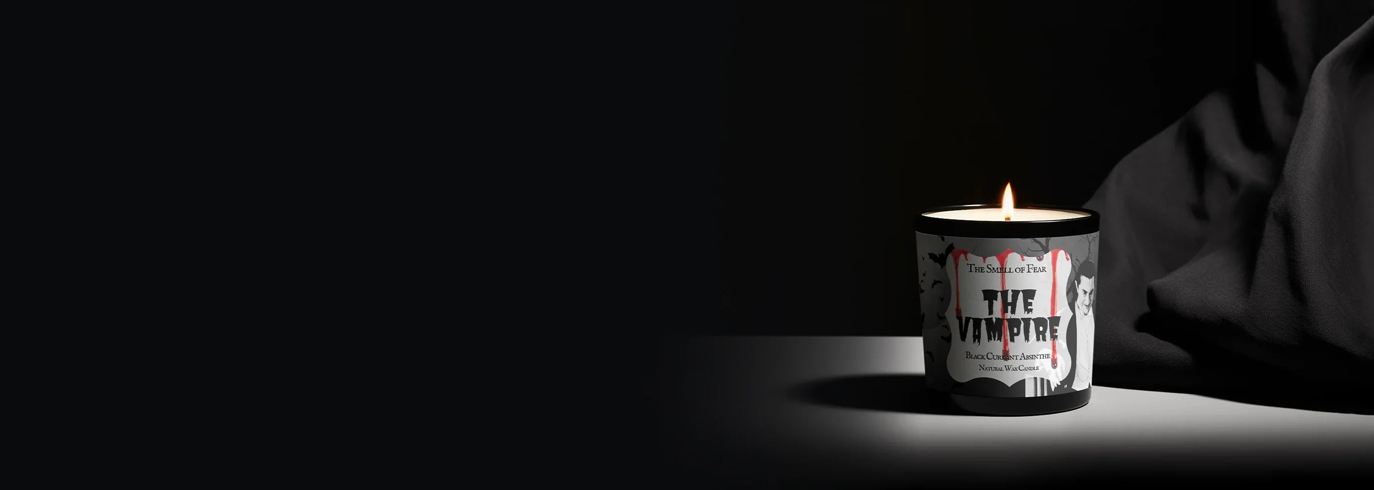 Lit horror candle labeled The Vampire, gothic vampire art, black background, eerie atmosphere