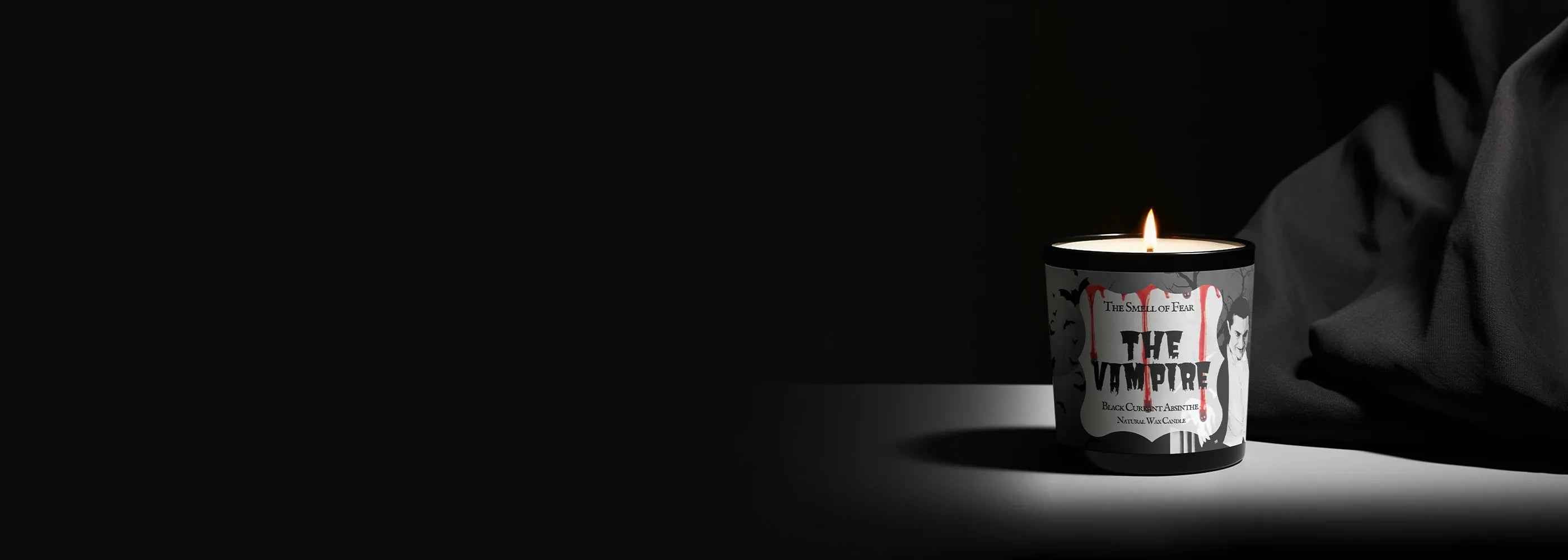 Lit horror candle labeled The Vampire, gothic vampire art, black background, eerie atmosphere